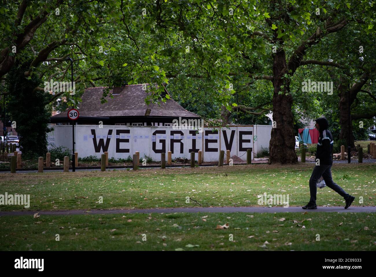 Un muro commemorativo con le parole 'We Grieve' e i nomi delle persone locali che sono morte a causa del COVID-19 e di altre cause non-coronavirus correlate come la malattia terminale durante l'epidemia di Coronavirus, scritto su accatamento intorno a Liberty Hall su Clapton Common, Londra. Foto Stock