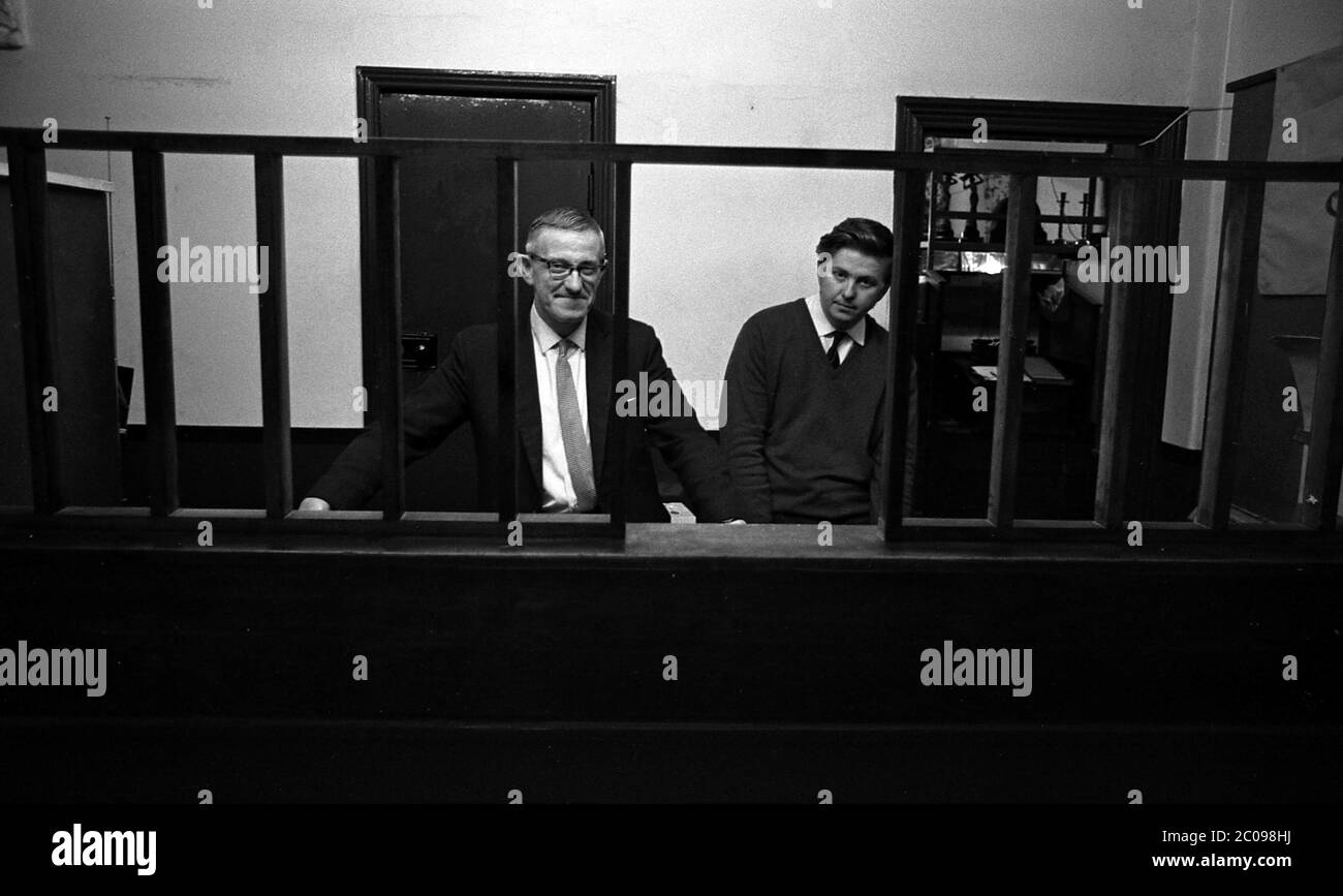 AJAXNETPHOTO. 14 SETTEMBRE 1969. PORTSMOUTH, INGHILTERRA. - DIETRO LE BARRE - (L-R) MR SWATRIDGE SENIOR E SON, TITOLARE DEL NEGOZIO DI GIOIELLERIA E DI PEDONI SITUATO IN ARUNDEL STREET. OFFICINA PROGRAMMATA PER LA DEMOLIZIONE. L'AZIENDA SI È TRASFERITA A FRATTON ROAD.PHOTO:JONATHAN EASTLAND/AJAX REF:356947 17 62 Foto Stock