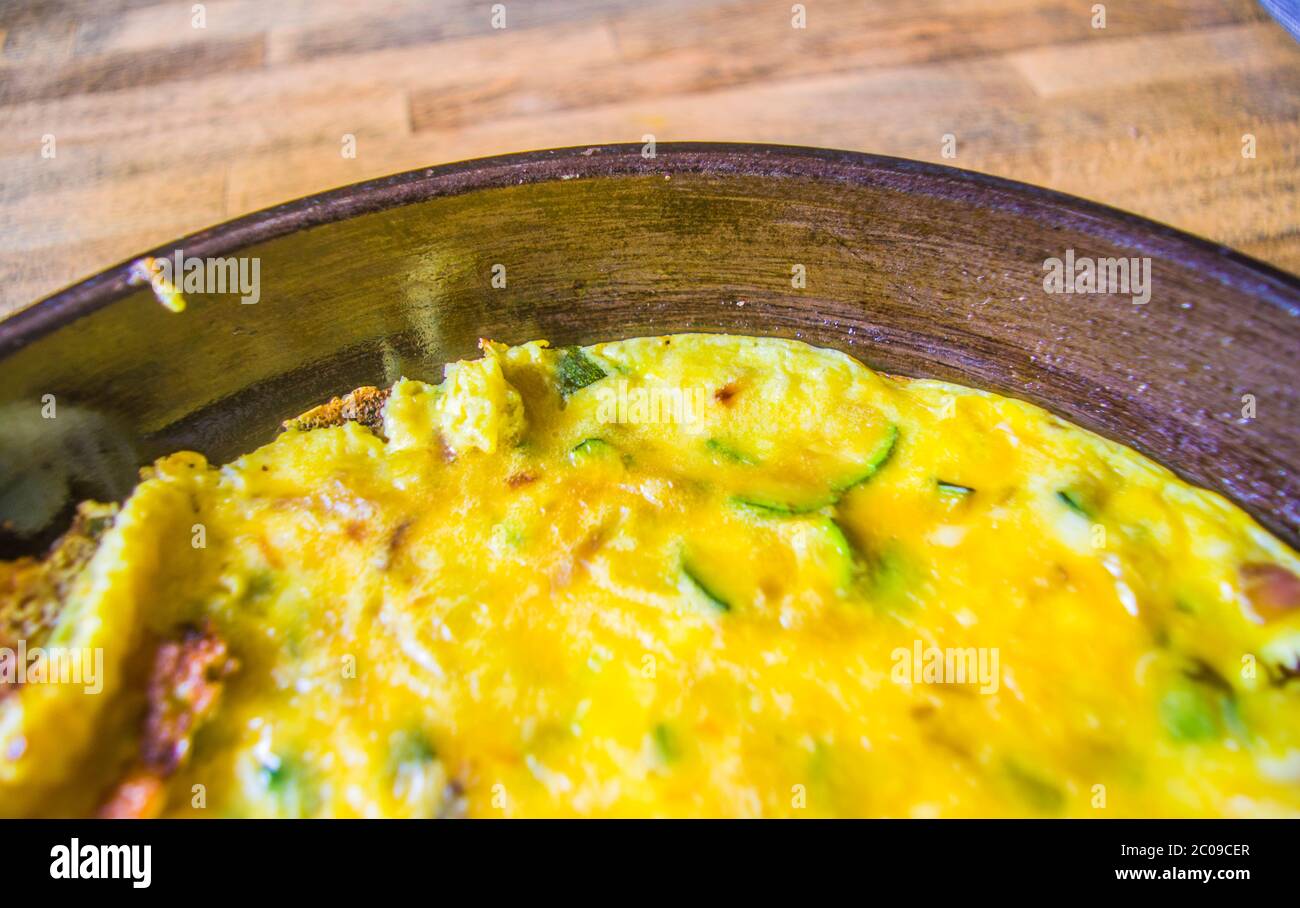 Padella con frittata a base di uova, zucchine, formaggio, olio, sale, pepe ed erbe aromatiche Foto Stock