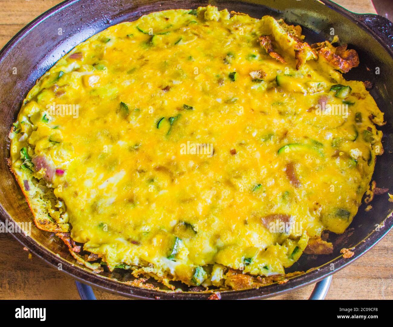 Padella con frittata a base di uova, zucchine, formaggio, olio, sale, pepe ed erbe aromatiche Foto Stock