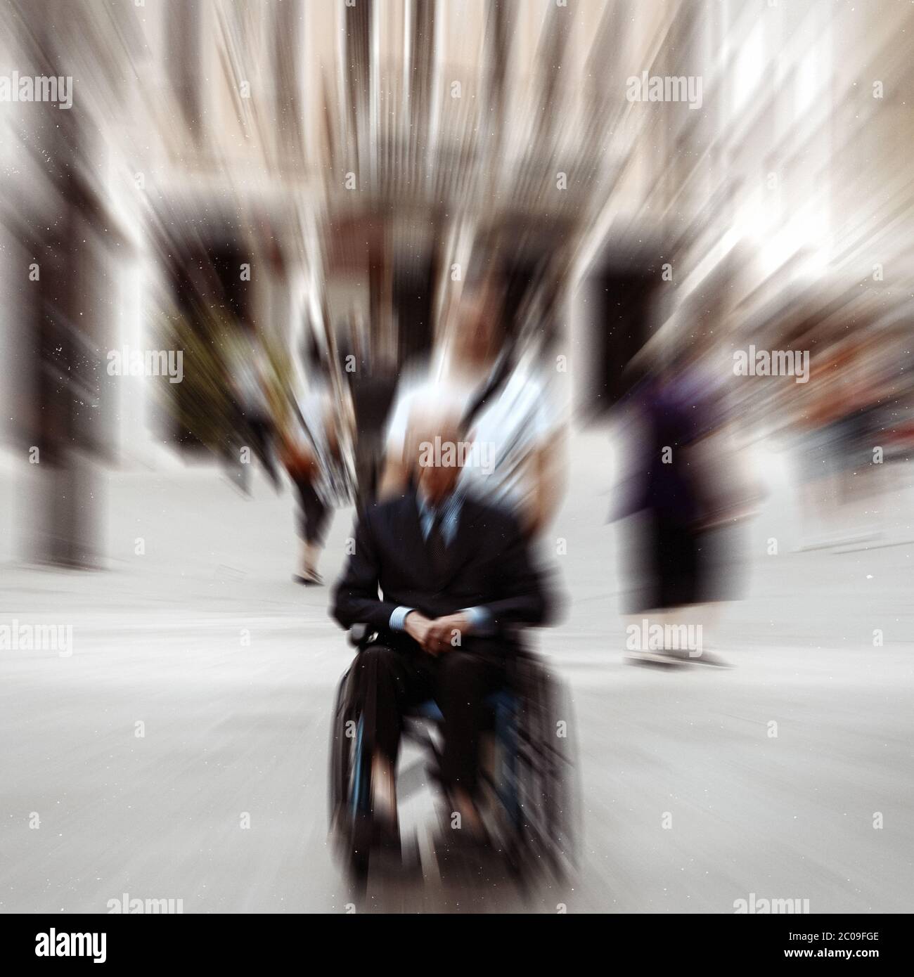 Sfondo astratto . Una persona disabile in sedia a rotelle su una strada cittadina. Effetto di sfocatura con zoom radiale filtro di sfocatura applicato, wit Foto Stock