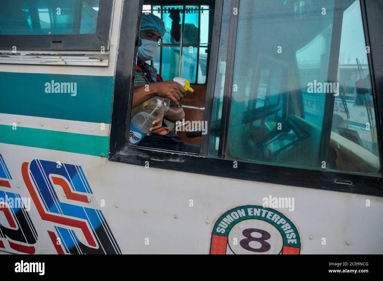 Un autista di autobus che spaving sanitizar sul suo stiring come misure preventive possibili in mezzo alla pandemia di Covid-19. Foto Stock