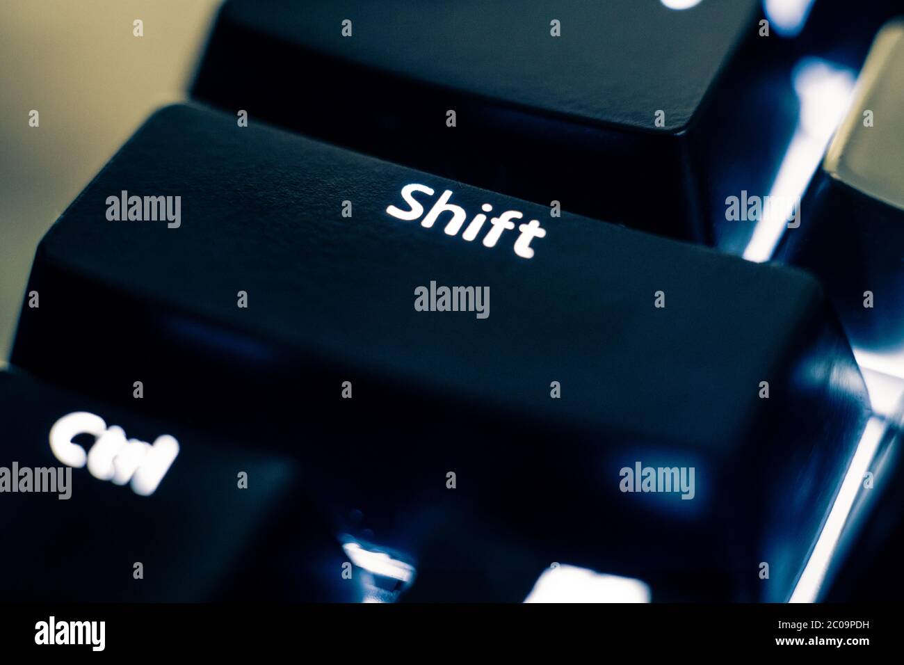Foto macro del tasto MAIUSC su una tastiera di commutazione meccanica. Le lettere sono incise sui cappucci in ABS di plastica nera per rivelare la retroilluminazione bianca a LED. Foto Stock