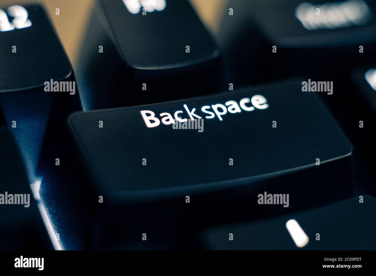 Foto macro del tasto backspace su una tastiera di commutazione meccanica. Le lettere sono incise sui cappucci in ABS in plastica nera per rivelare la retroilluminazione a LED bianchi. Foto Stock