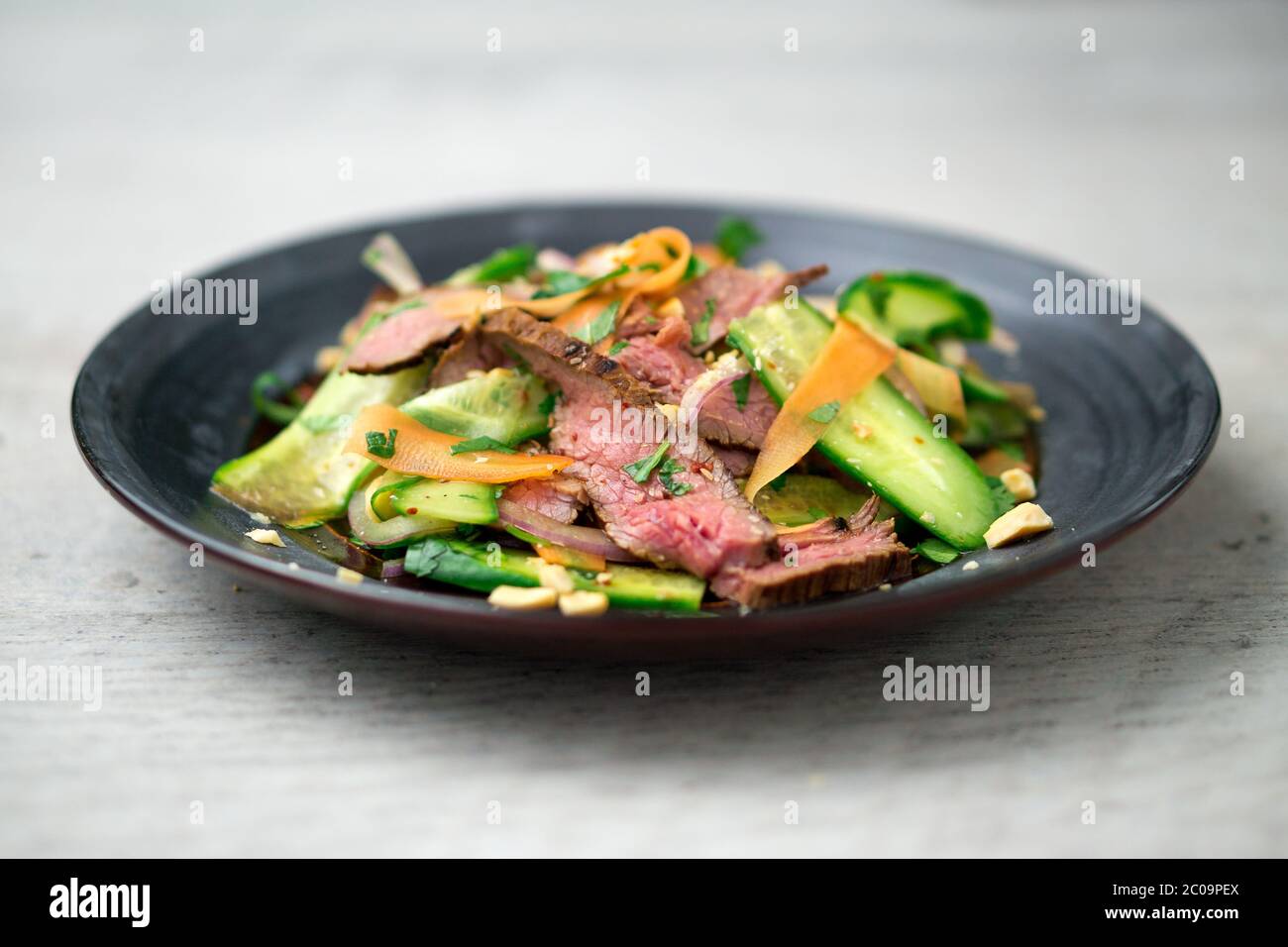 Vista angolare di un piatto di insalata di manzo asiatica. Ispirata alla cucina tailandese e vietnamita, questa insalata è fatta con verdure fresche e sane. Foto Stock