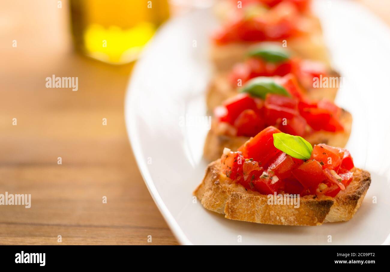 La bruschetta è un alimento italiano fatto di pomodori tritati, aglio, basilico ed erbe fresche su un pane tostato. Viene solitamente servito come snack o antipasti. Foto Stock