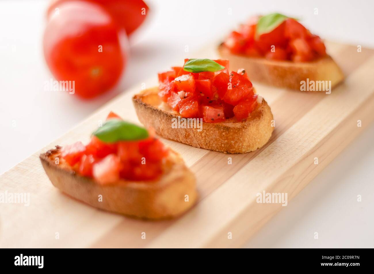 La bruschetta è un alimento italiano fatto di pomodori tritati, aglio, basilico ed erbe fresche su un pane tostato. Viene solitamente servito come snack o antipasti. Foto Stock