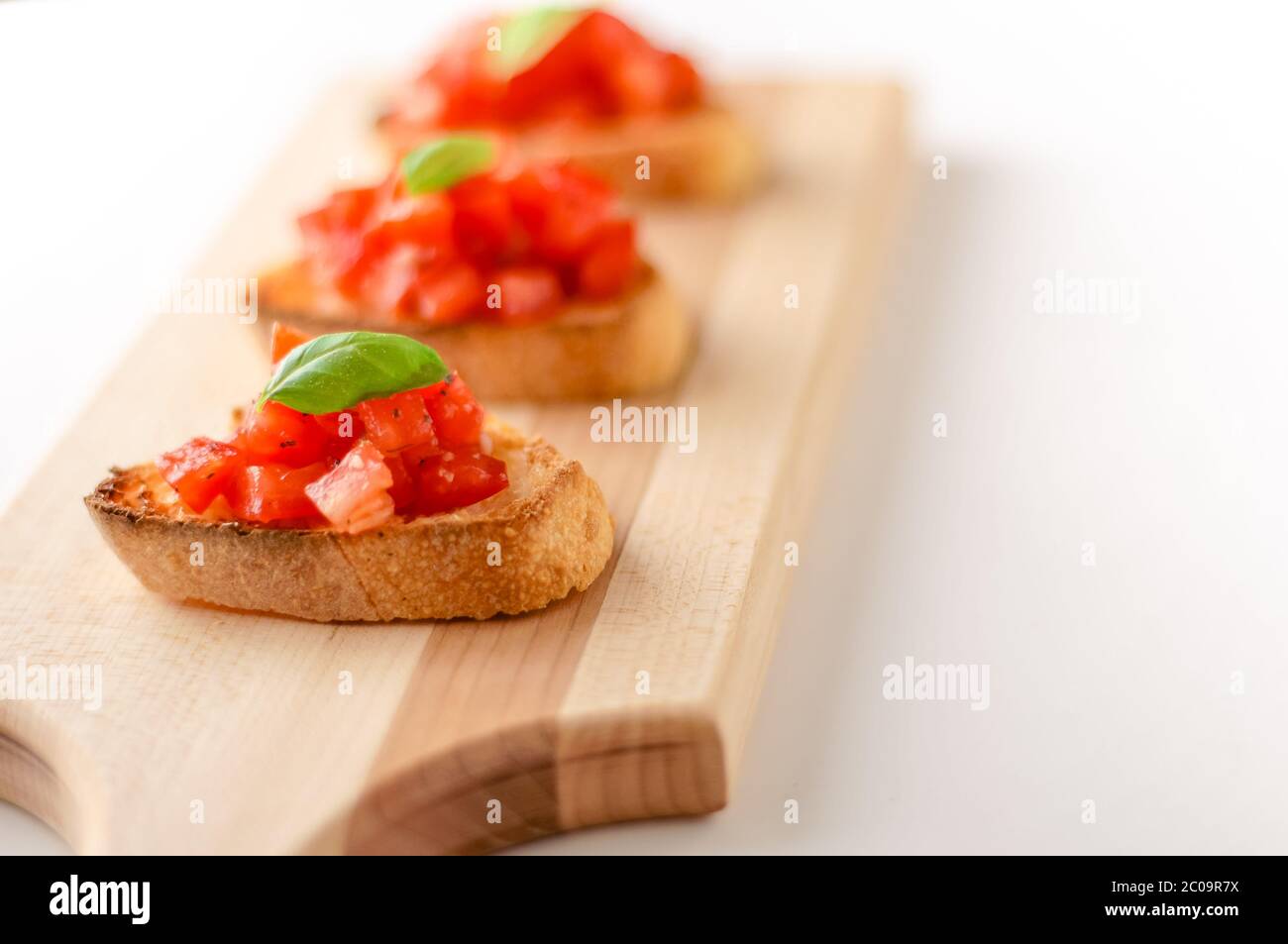 La bruschetta è un alimento italiano fatto di pomodori tritati, aglio, basilico ed erbe fresche su un pane tostato. Viene solitamente servito come snack o antipasti. Foto Stock