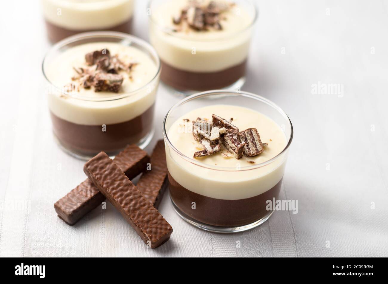 Mousse al cioccolato a strati e cheesecake senza cottura con biscotti al wafer ricoperti di cioccolato e crumb. In ciotole da dessert in vetro trasparente. Su sfondo bianco. Foto Stock