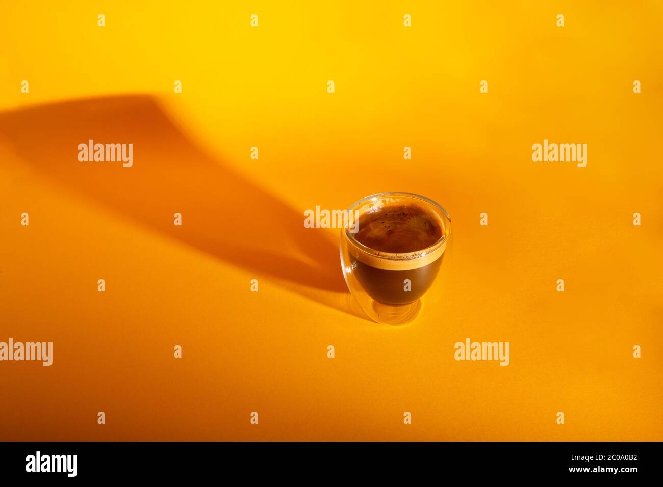 Espresso cremoso appena preparato in una tazza di caffè in vetro isolata su sfondo giallo, primo piano con spazio per la copia Foto Stock