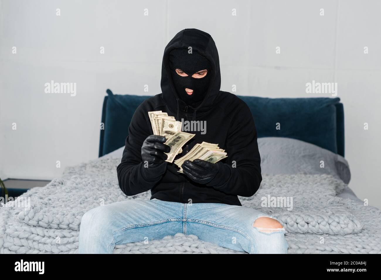 Ladro in maschera e guanti di pelle contando dollari sul letto Foto stock -  Alamy