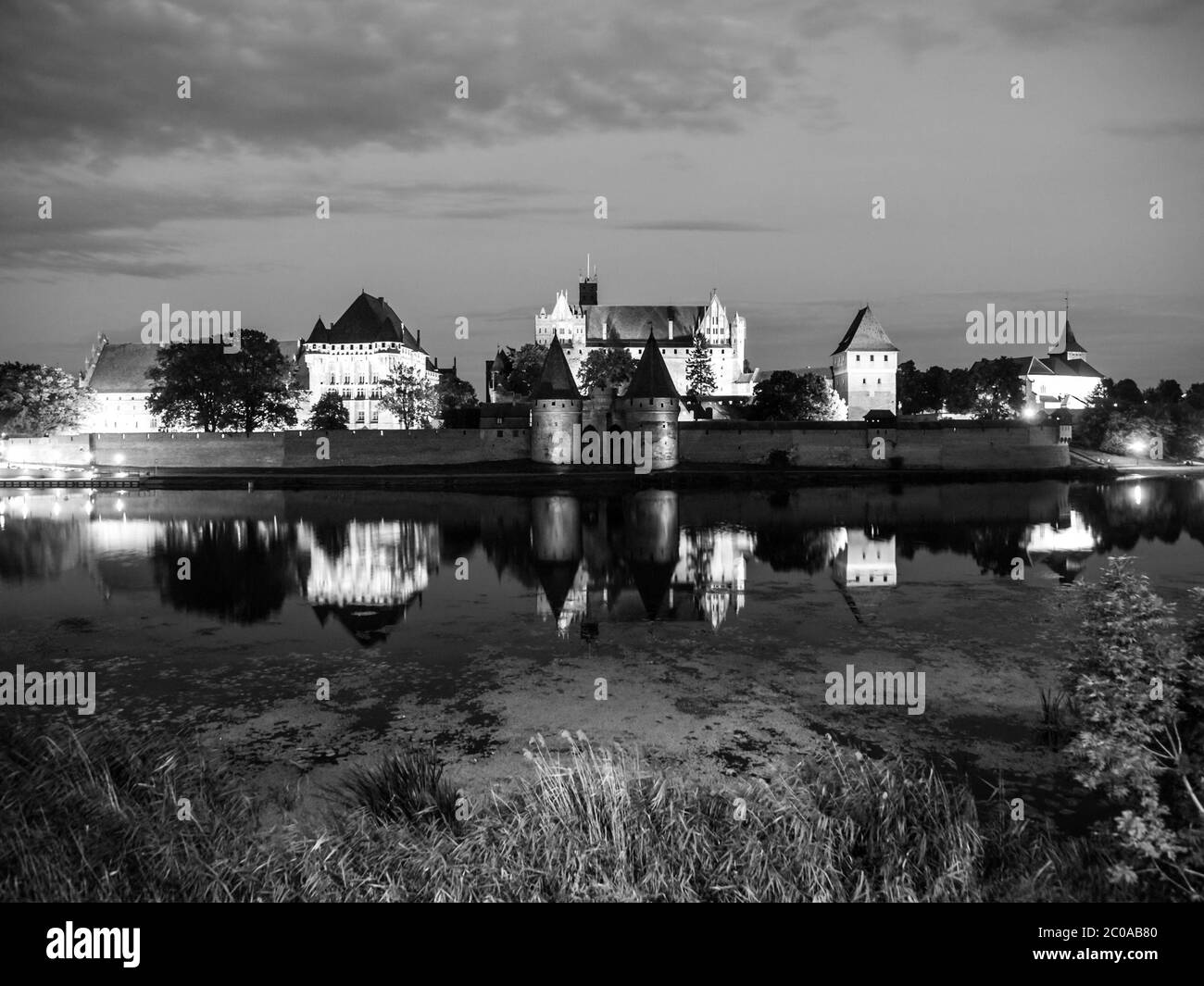 Castello di Malbork di notte con riflessione nel fiume Nogat, Polonia. Immagine in bianco e nero. Foto Stock