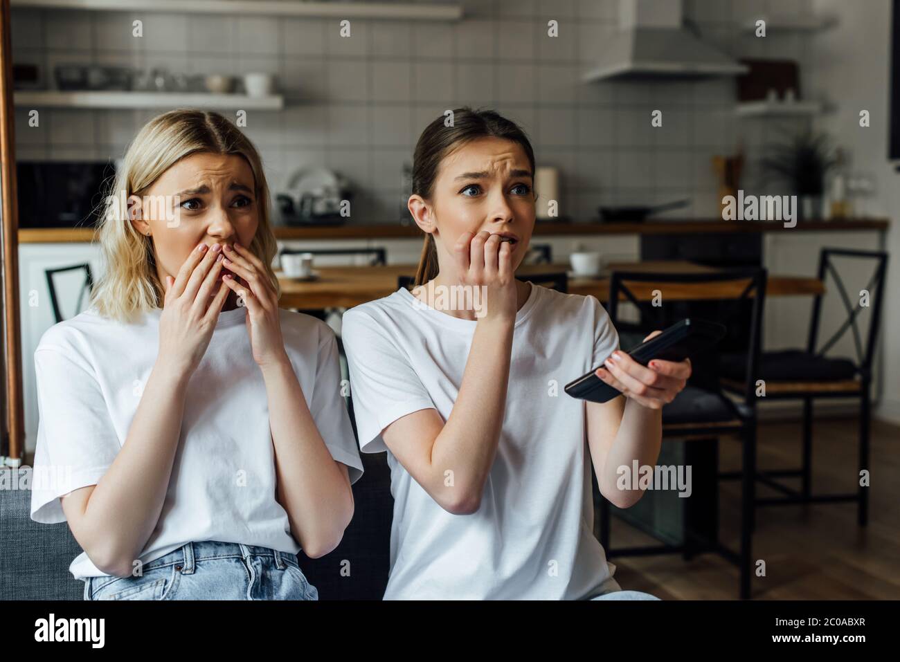 Sorelle scioccate e spavate che guardano la tv sul divano a casa Foto Stock