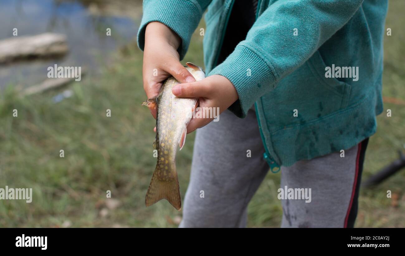 ragazzo che tiene un pesce catturato di recente Foto Stock