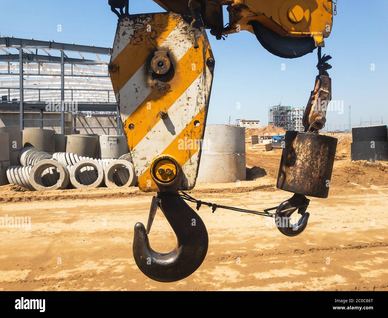 Gancio per gru con strisce gialle sullo sfondo di un cantiere vuoto. Foto di alta qualità Foto Stock