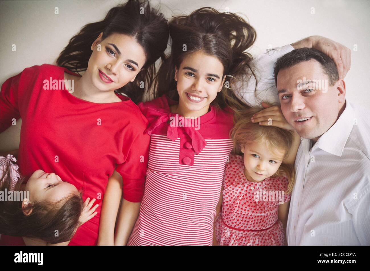 Felice famiglia giovane con bambini sdraiati su un pavimento Foto Stock