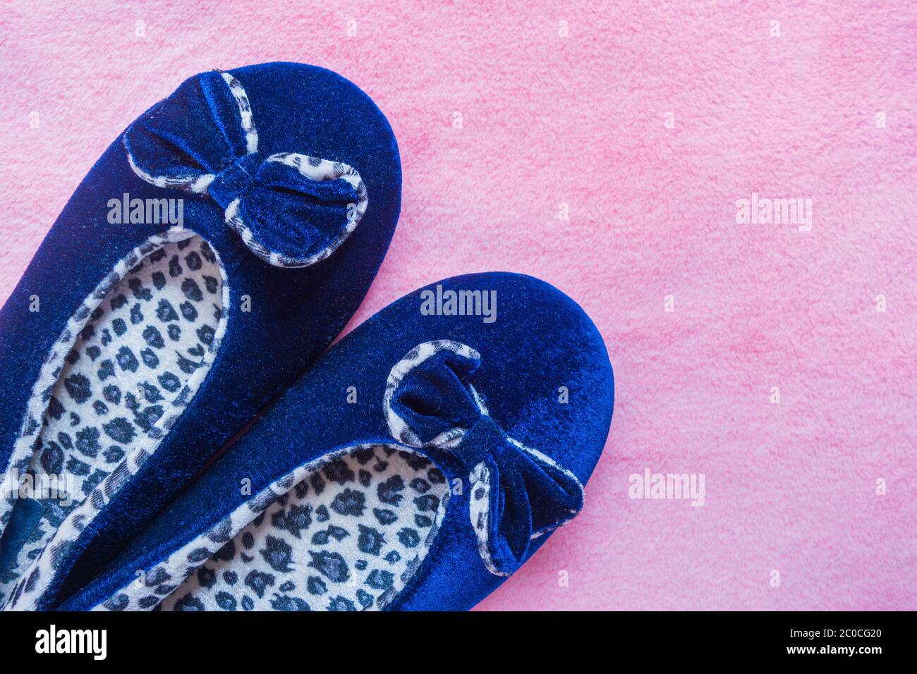 Ciabatte Blue leopard su un soffice tappeto rosa. Abbigliamento domestico per donna o bambini. Il concetto di calore e comfort domestici. Messa a fuoco selettiva. Foto Stock