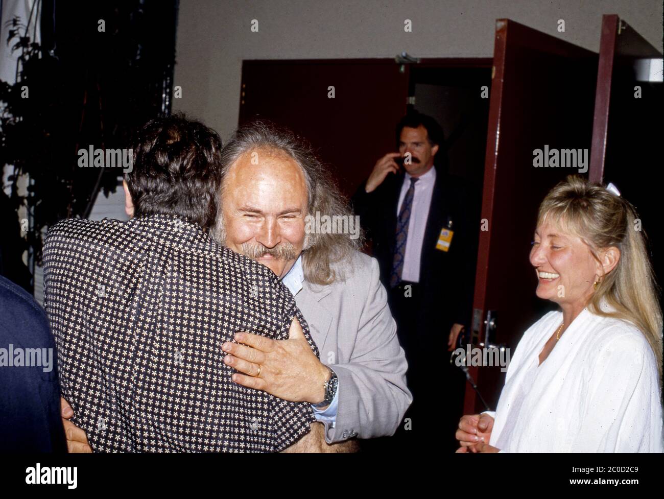 Il musicista David Crosby con la moglie Jan Dance abbracci Robin Williams al Comic Relief benefit performance a Los Angeles, CA circa anni ottanta. Foto Stock