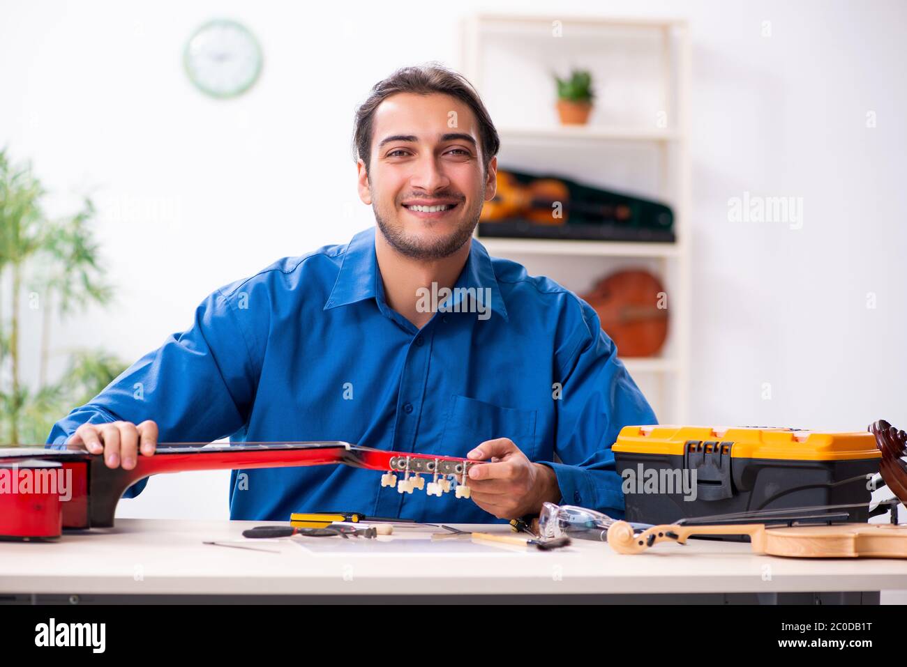 Giovane uomo riparatore riparando la chitarra Foto Stock