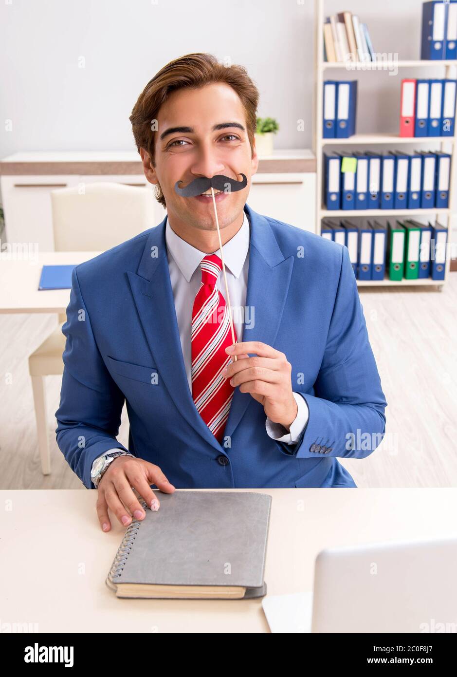 La divertente bisinessman con baffi finti in ufficio Foto Stock