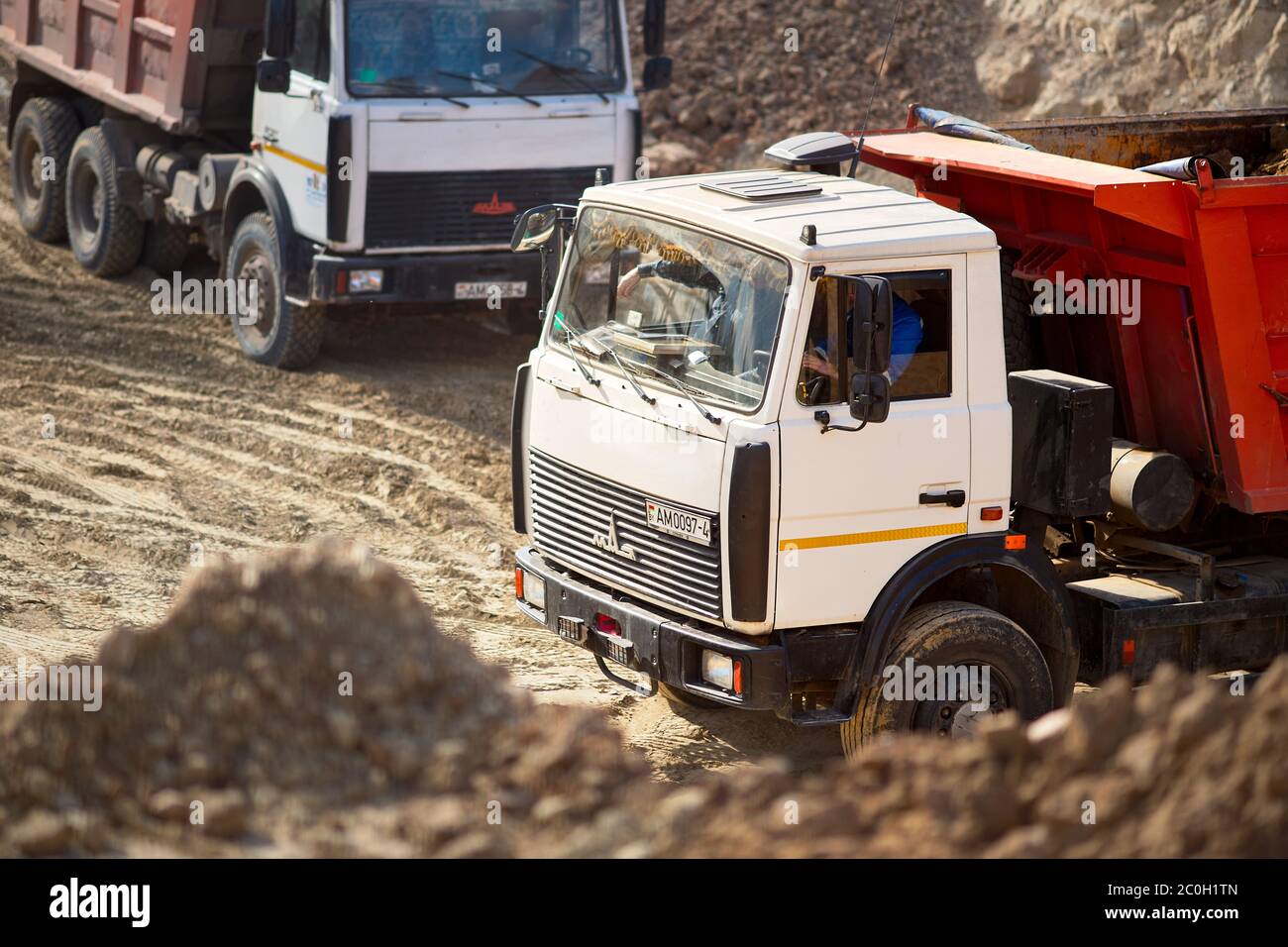 GRODNO, BIELORUSSIA - APRILE 2020: Due camion pesanti multi-ton MAZ che esportano minerali da miniera a cielo aperto. Concetto di trasporto e trasporto Foto Stock