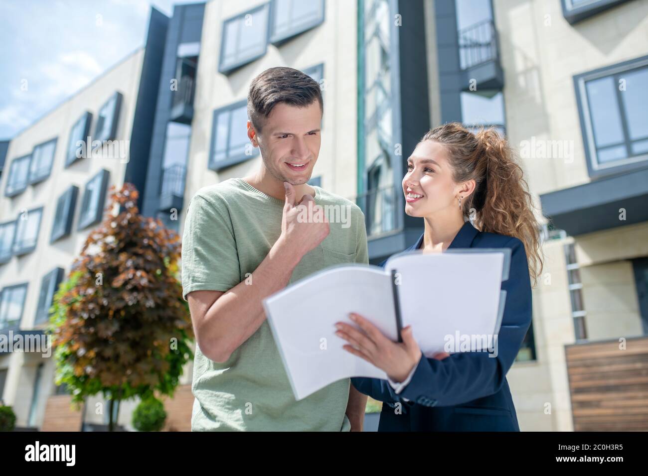 Uomo dai capelli scuri che legge i termini del contratto e che guarda pensieroso Foto Stock