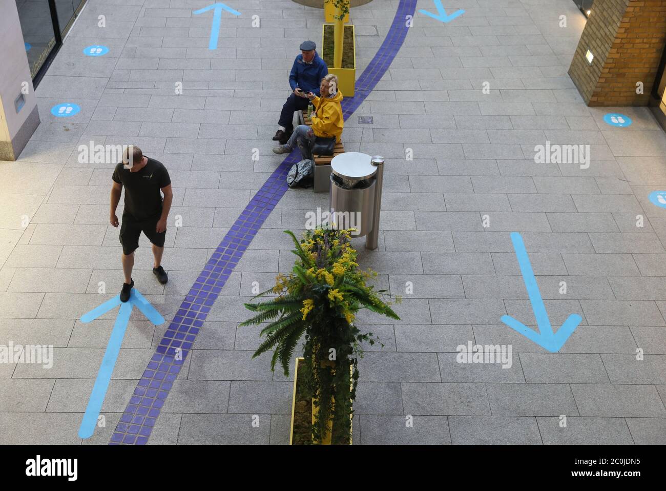 Un uomo installa delle frecce sul pavimento per guidare gli acquirenti attraverso il sistema di sola andata nel centro commerciale Victoria Square, Belfast, dopo che tutti i centri commerciali e i rivenditori sono stati dati il via libera per riaprirsi in un significativo rilassamento delle restrizioni di blocco del coronavirus nell'Irlanda del Nord. Foto Stock