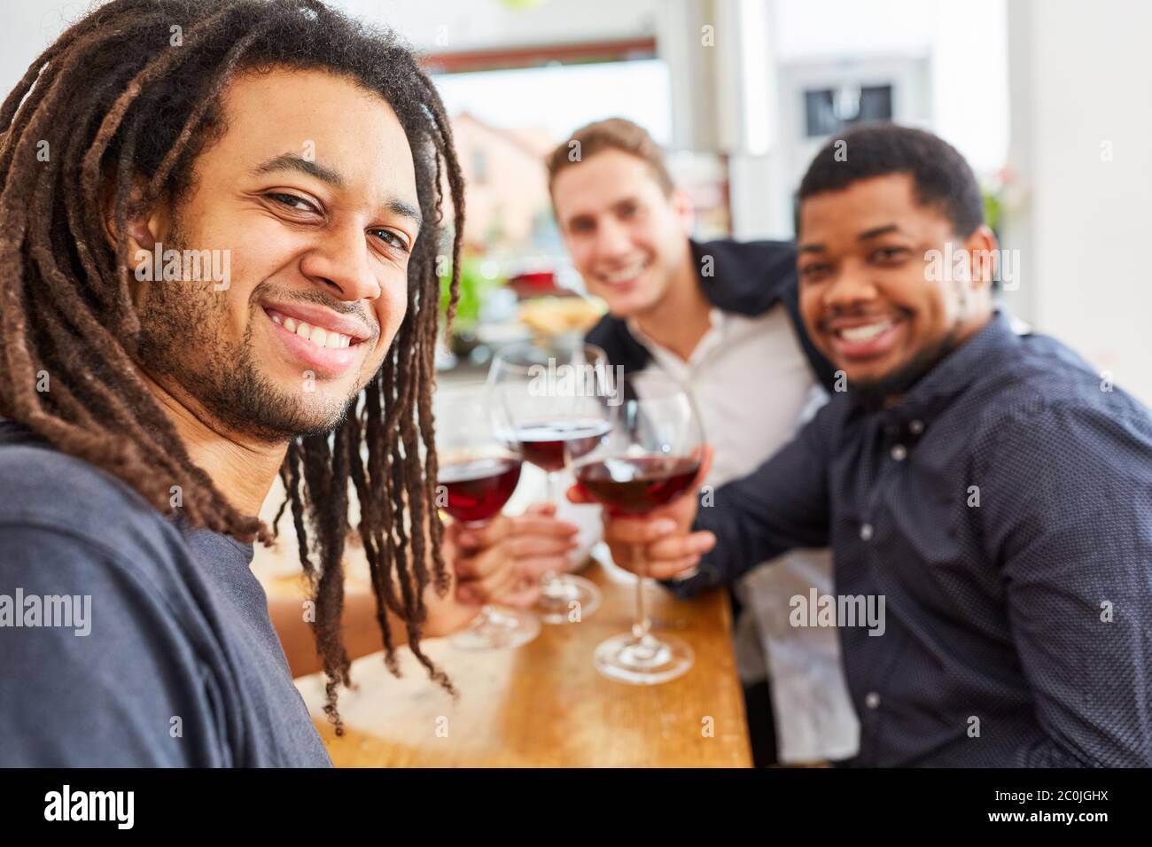 Uomini felici come amici che bevono vino insieme in cucina Foto Stock
