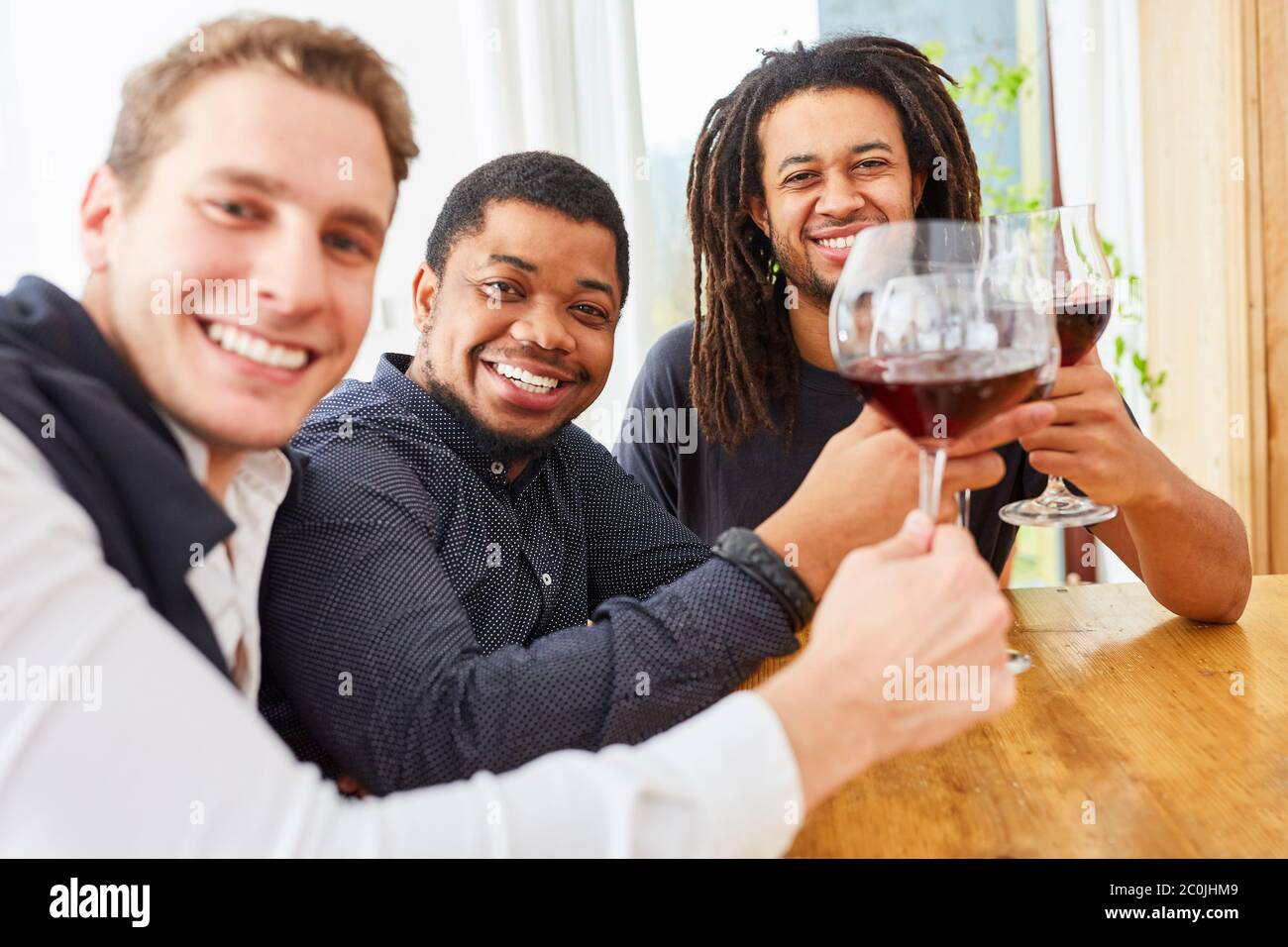 Gruppo di uomini che bevono vino a casa con un bicchiere di vino rosso Foto Stock