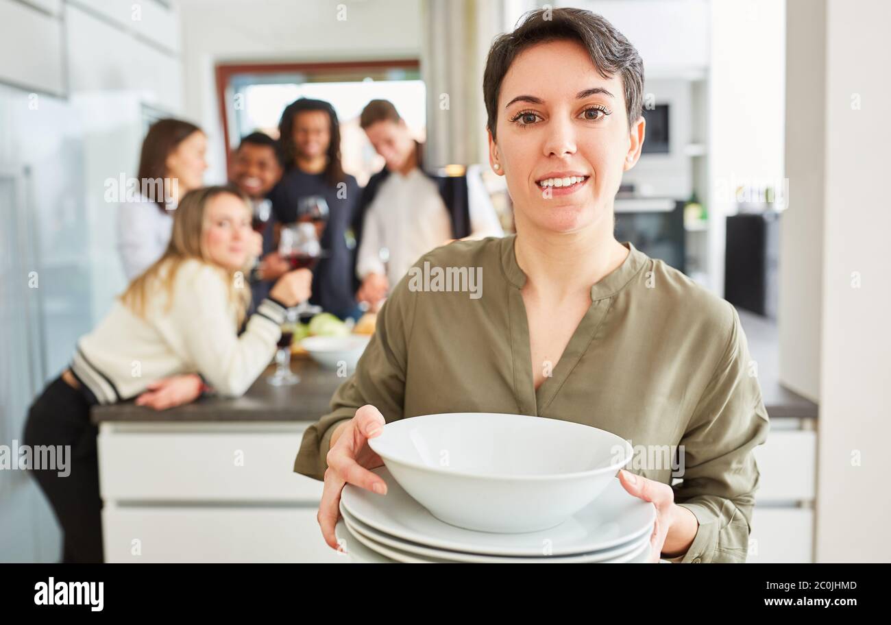 Giovane donna che porta i piatti in cucina condivisa di fronte ad un gruppo di studenti Foto Stock