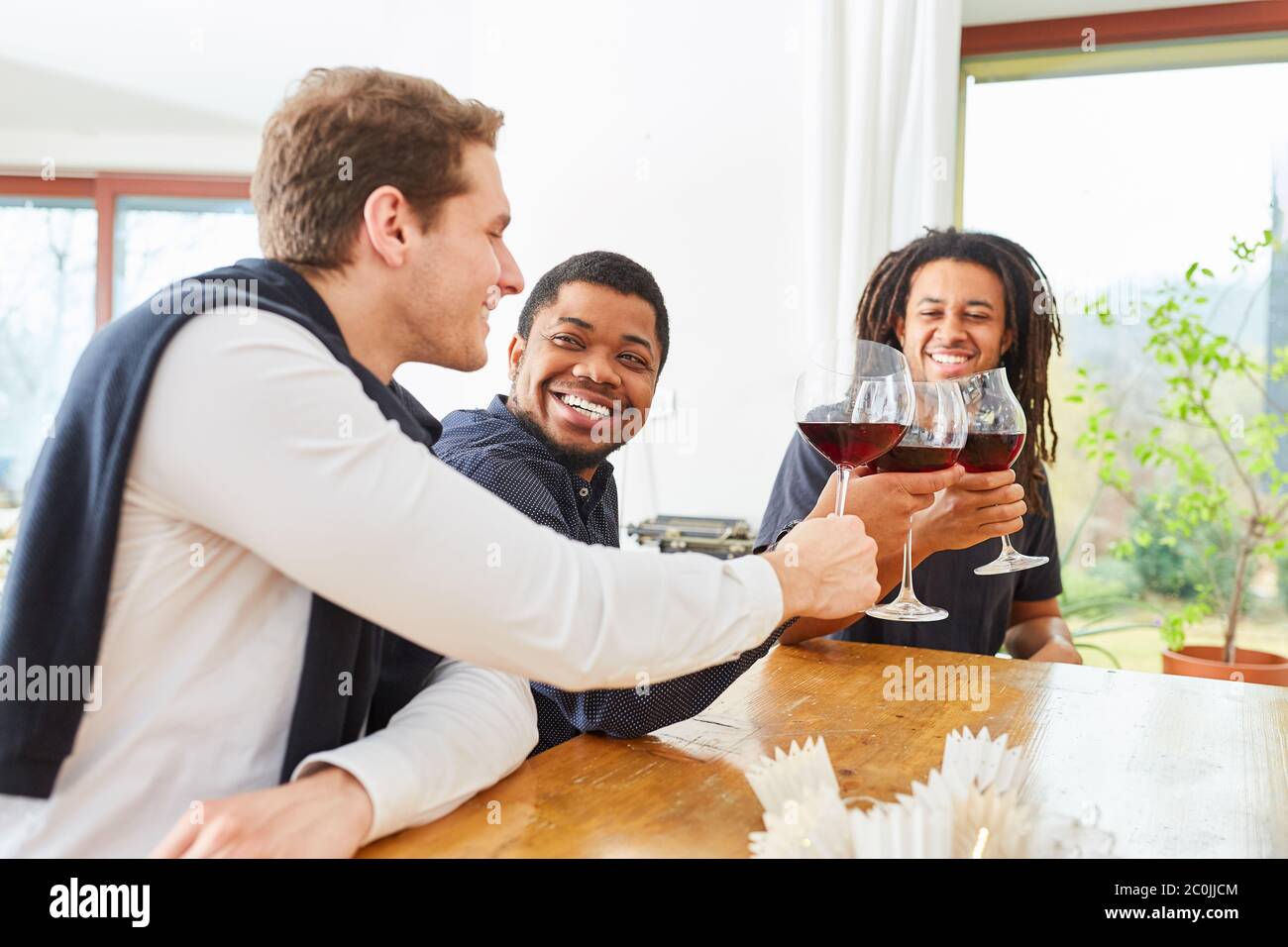 Gruppo di uomini come amici bere un bicchiere di vino rosso insieme e ridere insieme Foto Stock