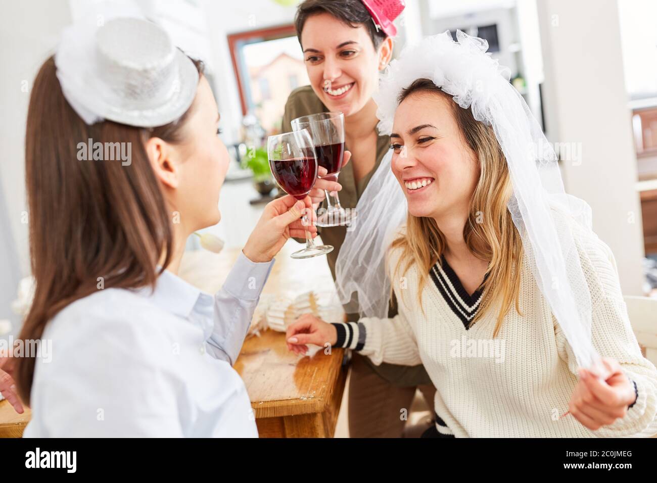 Le girlfriends ridenti festeggiano con la gallina durante la festa di gallina prima di sposarsi con un bicchiere di vino Foto Stock