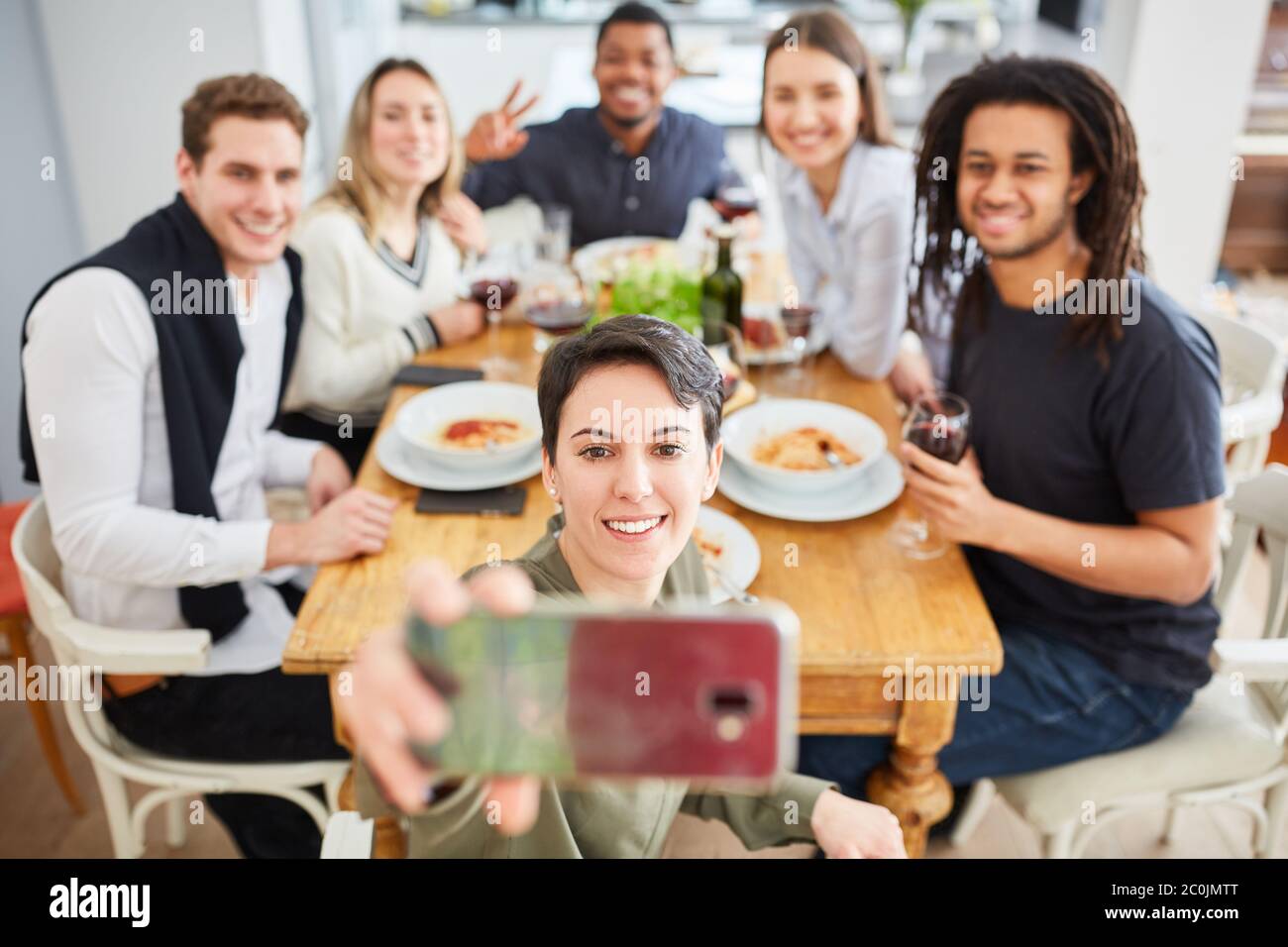 Gli studenti prendono selfie con smartphone dal mangiare insieme al tavolo di un appartamento condiviso Foto Stock