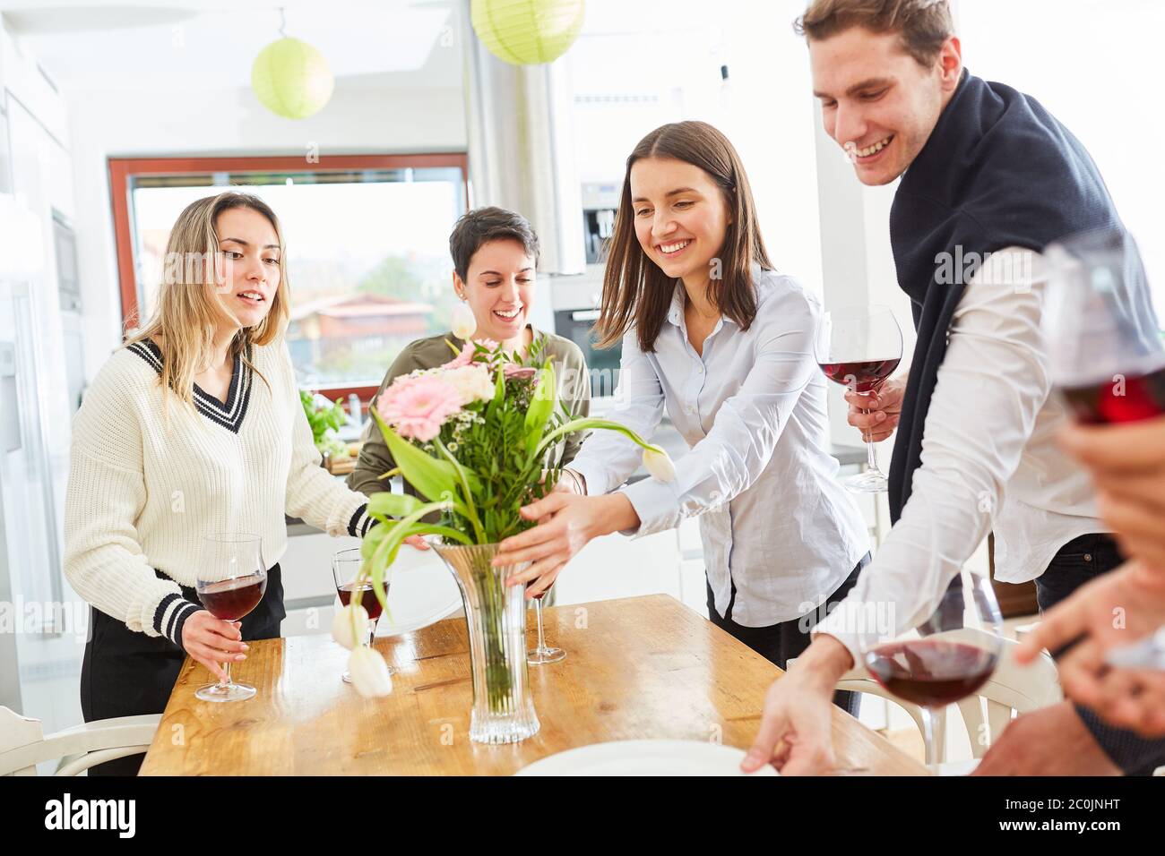 Amici felici decorano e fisso tavolo per pranzo insieme in cucina condivisa Foto Stock