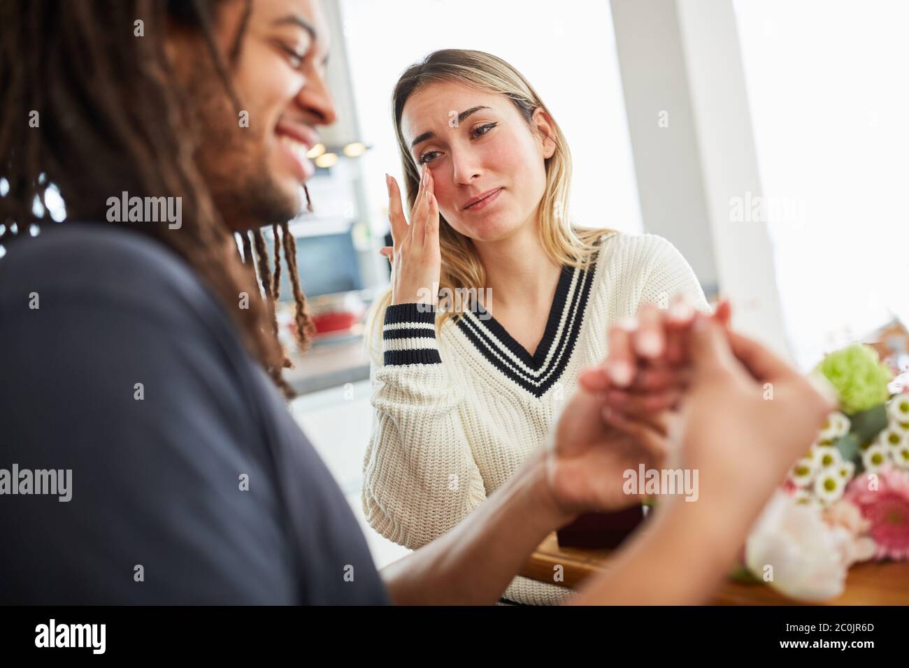 Giovane donna felice salviette strappano per gioia a proposta di matrimonio mentre l'uomo mette sul suo anello Foto Stock