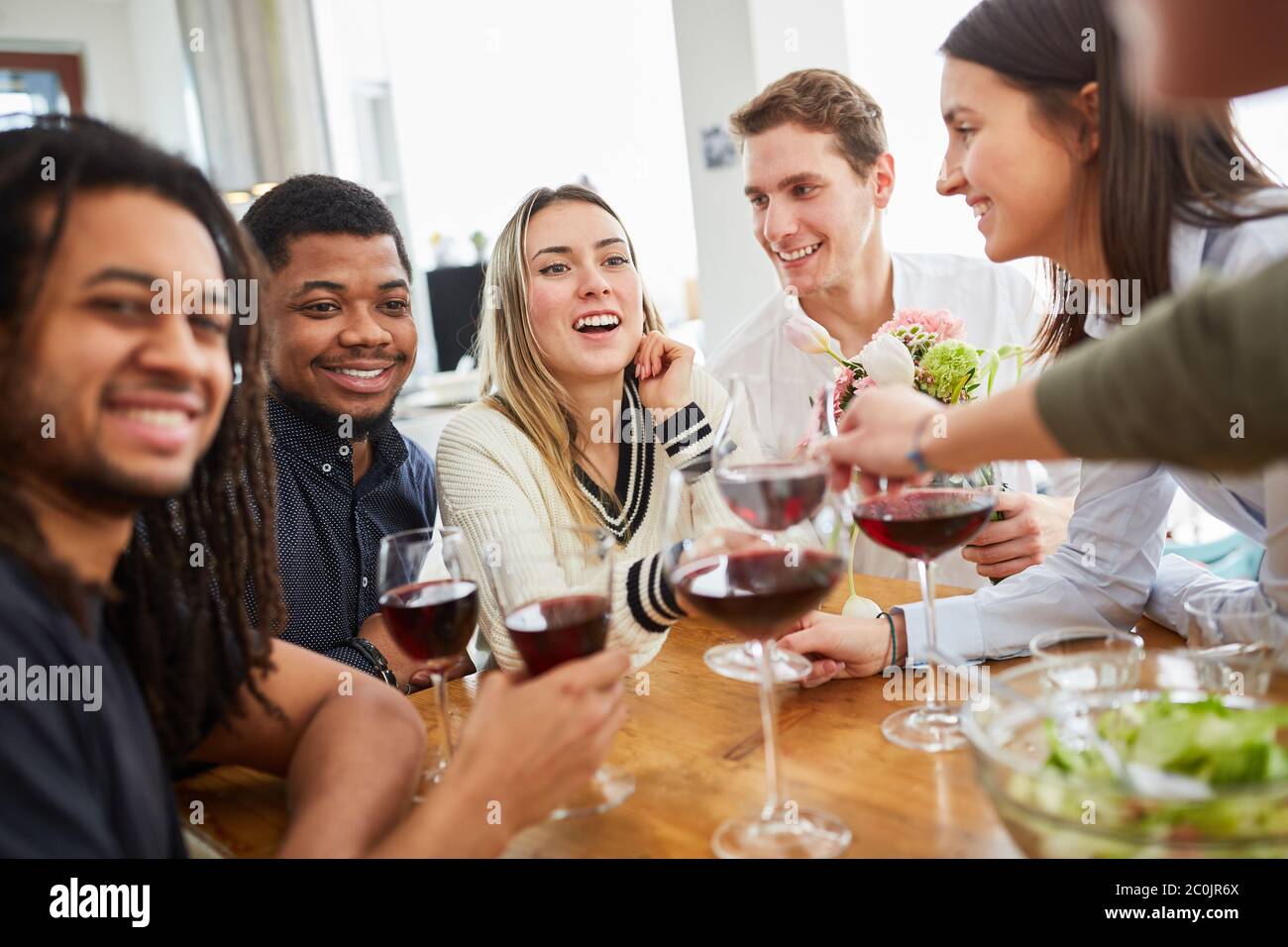 Felici amici con un bicchiere di vino rosso insieme al tavolo in attesa di sorpresa Foto Stock