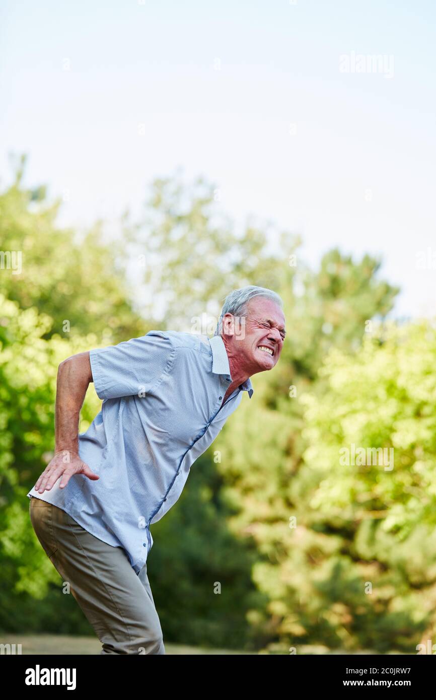 L'uomo anziano in natura ottiene un lombago nella parte posteriore Foto Stock
