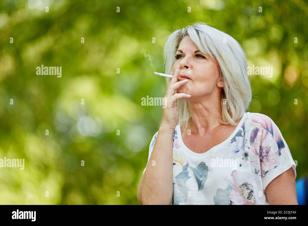 Vecchia donna che fuma una sigaretta in natura Foto Stock