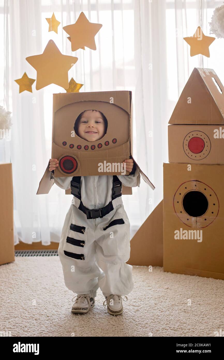 Dolce bambino, vestito da astronauta, giocando a casa con razzo di cartone  e casco fatto a mano da scatola Foto stock - Alamy