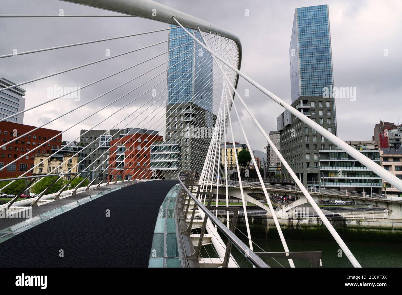 Vista del moderno ponte Zubizuri oltre il fiume Nervión con edifici in background nella città di Bilbao in Spagna. Foto Stock