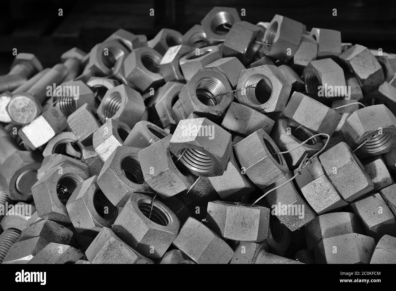 Pila di dadi esagonali impilati all'interno di un magazzino di stoccaggio Foto Stock