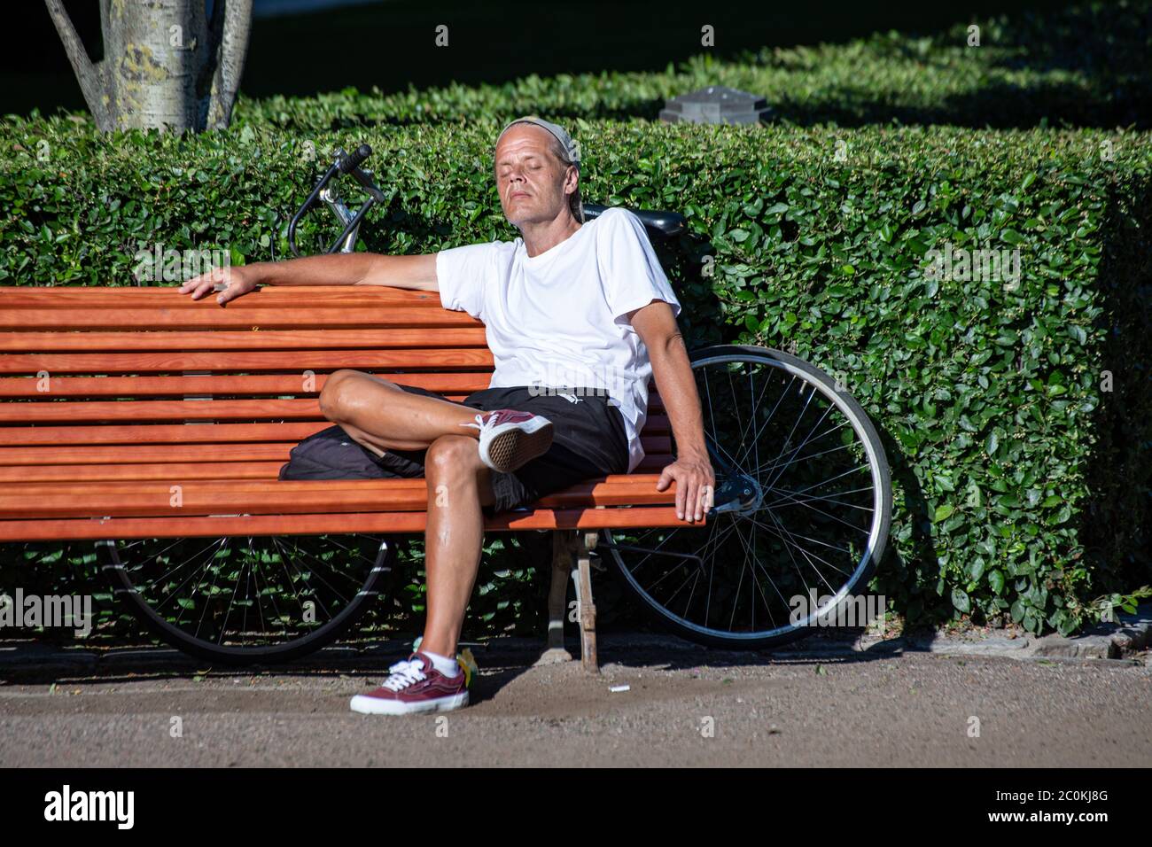 Ciclista godendo il sole serale su una panchina nel Parco Esplanadi a Helsinki, Finlandia Foto Stock