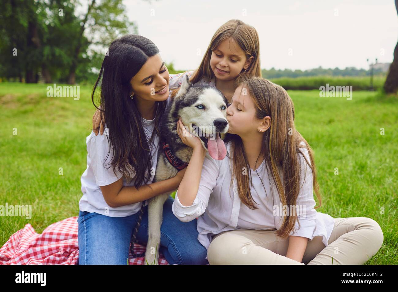 Due belle sorelle con la madre e il cane Husky al parco. Felice famiglia con il loro animale domestico in campagna Foto Stock