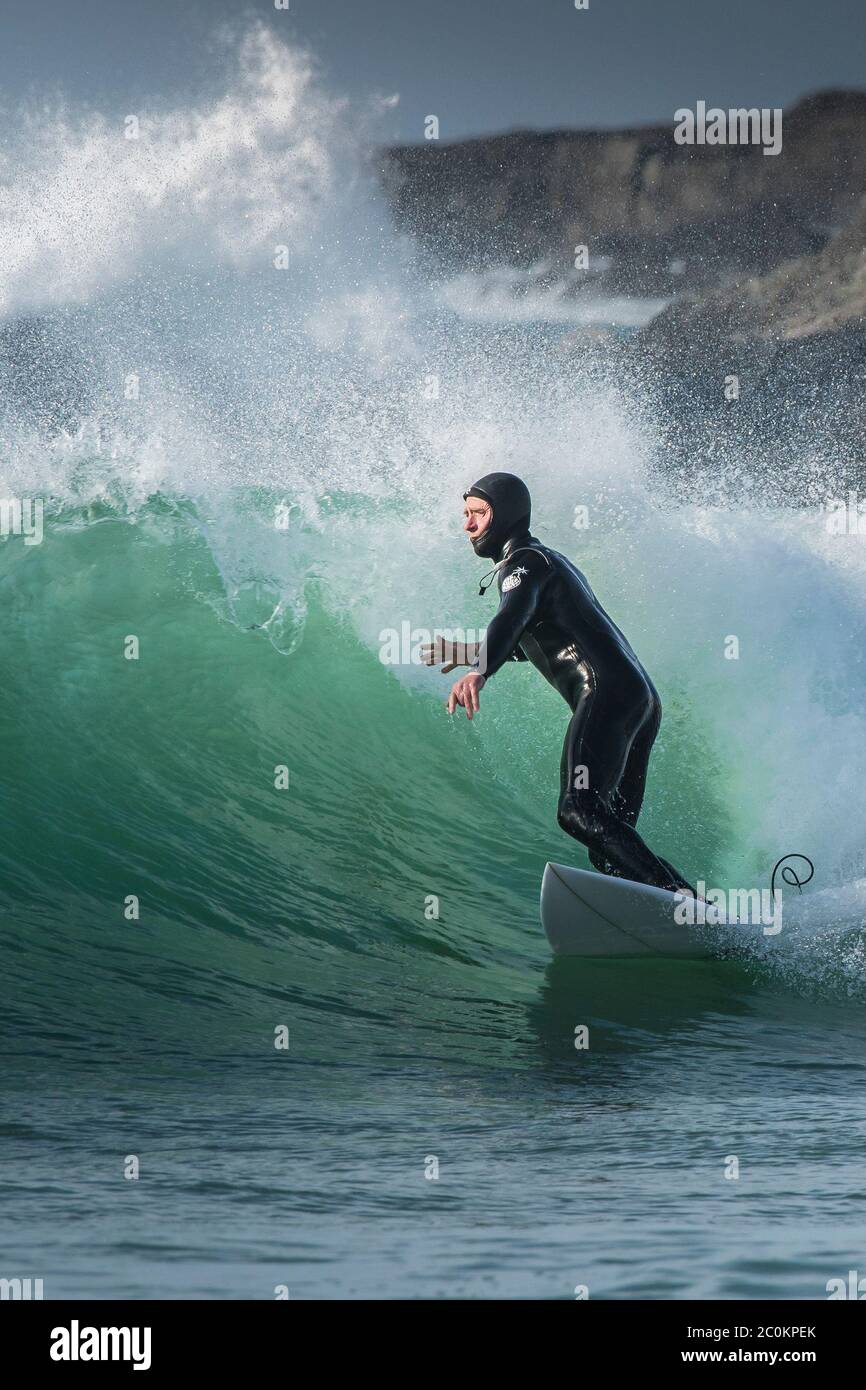 Un surfista a cavallo di un onda al Fistral a Newquay in Cornovaglia. Foto Stock