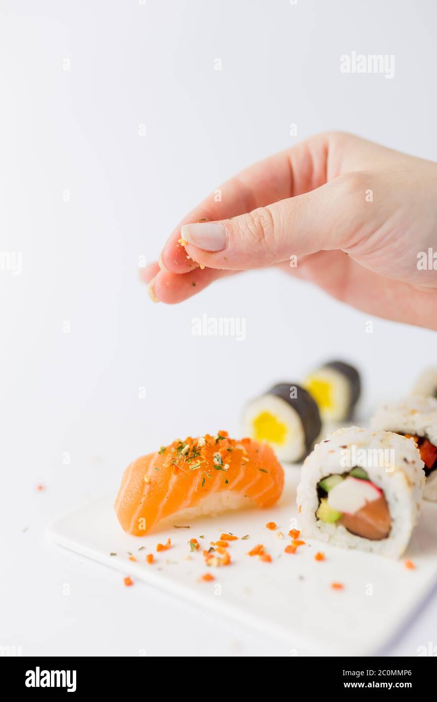 Primo piano dello chef con aggiunta di spezie sul set di sushi. Foto Stock