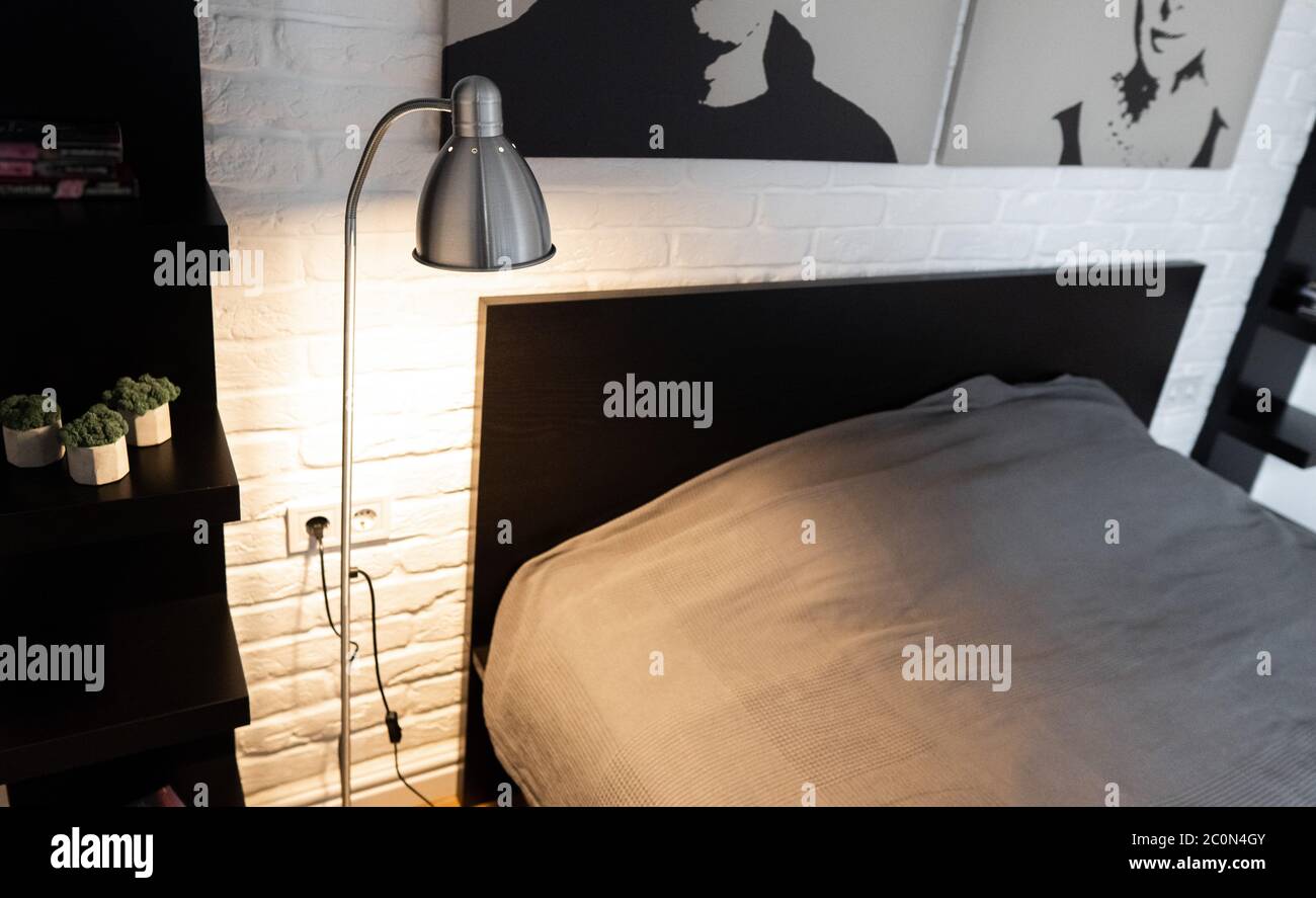 Lampada da lavoro in metallo con luce di lettura regolabile. Lampada da terra downbridge in acciaio con braccio lungo e paralume opaco vicino al letto in bianco e nero moderno Foto Stock