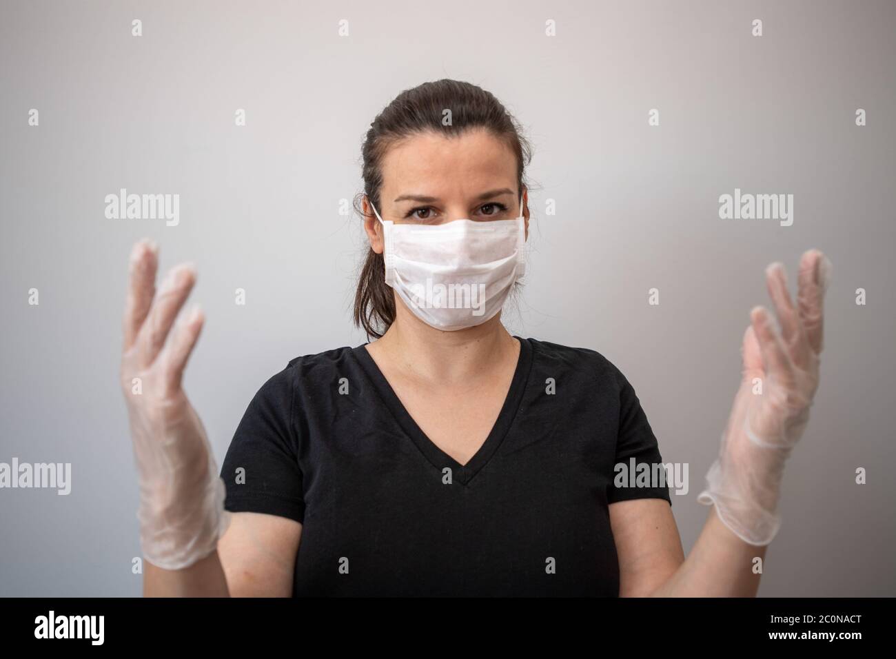 Donna attraente guardando la macchina fotografica indossare maschera medica colore bianco viso e guanti di protezione da COVID19 o corona virus. Cura personale durante pande Foto Stock