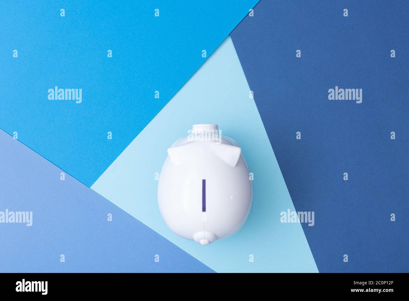 Bianco piggy bank visto dall'alto con uno sfondo fresco colorato fatto da cartoncino Foto Stock