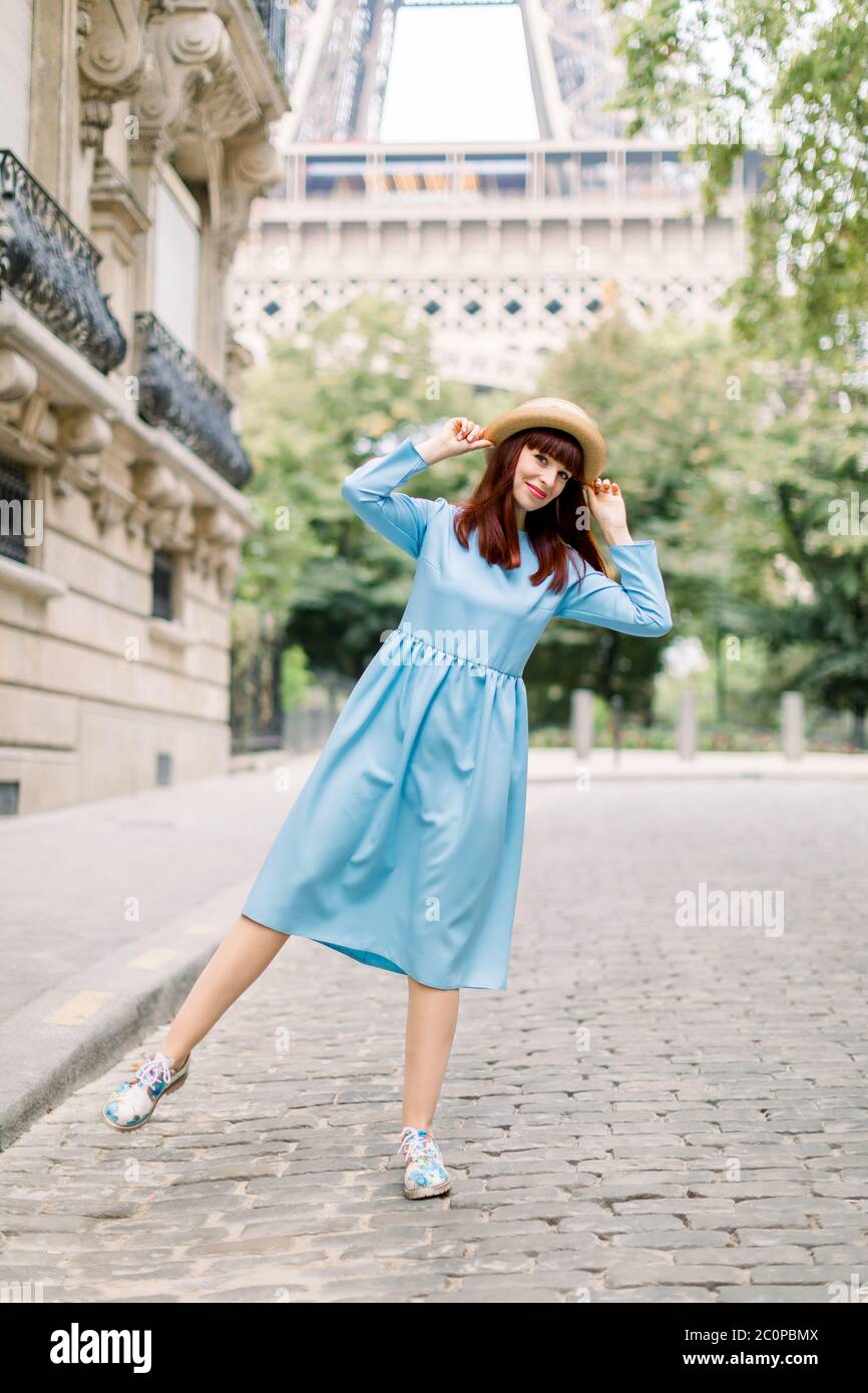Bella giovane donna con capelli rossi, con un elegante abito blu e cappello  di paglia, a
