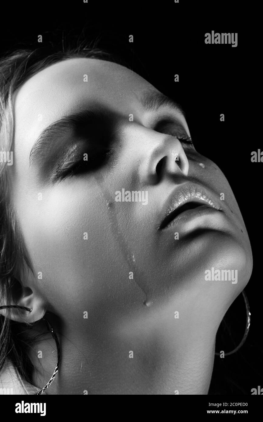 donna triste piangendo con occhi chiusi su sfondo nero, ritratto closeup, monocromatico Foto Stock